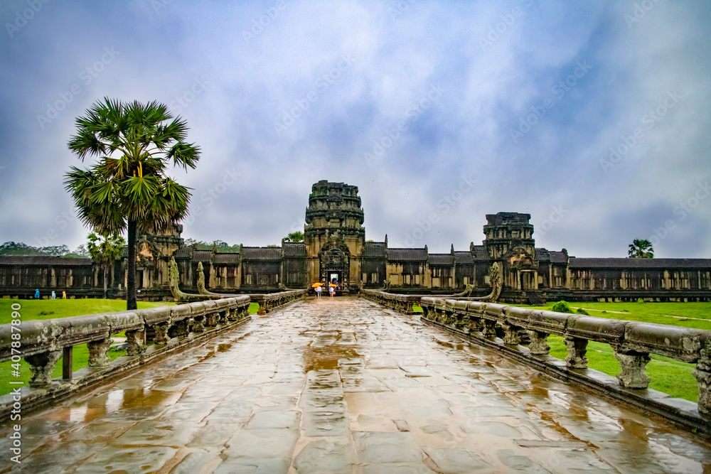  Angkor Wat-largest temple in the world. It is raining. Tourists walk around the temple