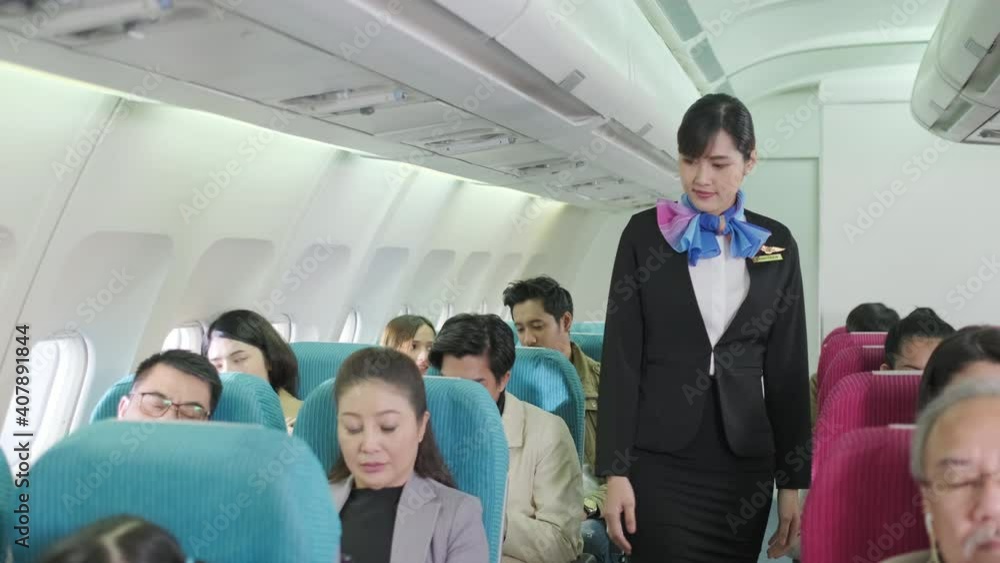 Stewardess in uniform looking all passengers to fasten seat belt while sitting on the airplane for safety flight. The security system is rigorous. International Airlines. Long trip for vacatio Stewardess in uniform looking all passengers to fasten seat belt while sitting on the airplane for safety flight. The security system is rigorous. International Airlines. Long trip for vacatio