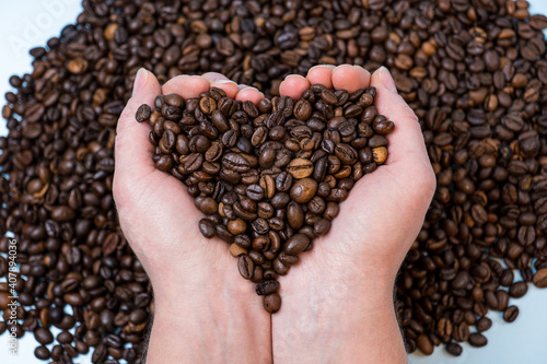 coffee beans close-up on the palm in the shape of a heart against the background of other coffee beans