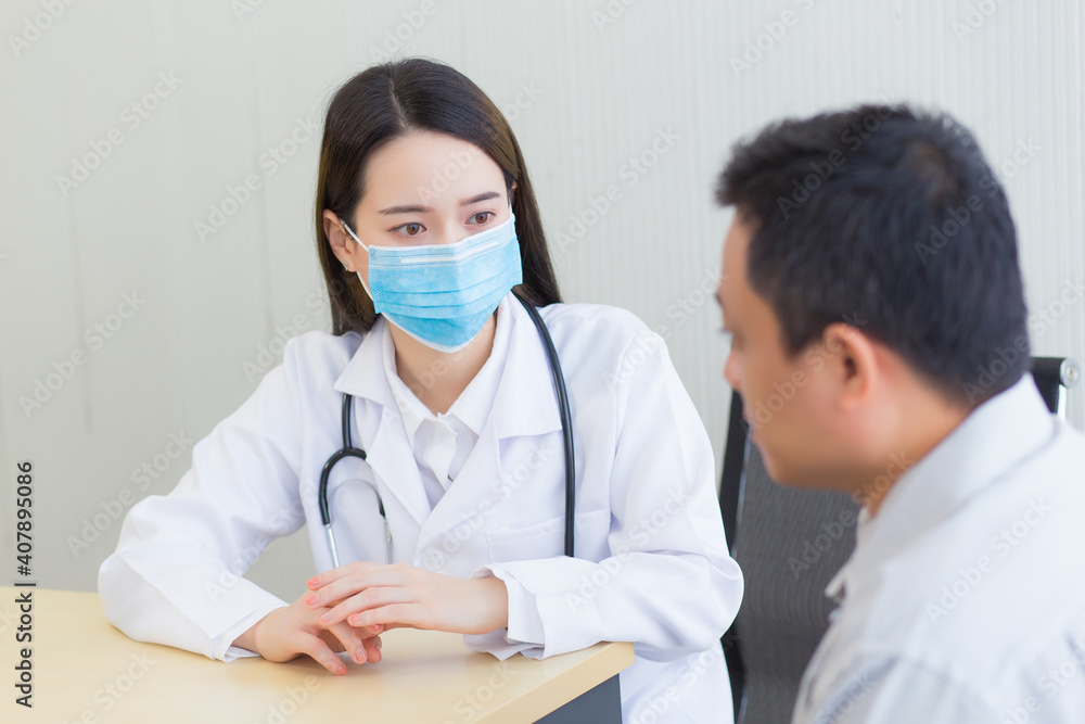 Both of Asian woman doctor and a man patient wear medical face mask to protect infectious disease (Covid 19) while check up health in hospital. Both of Asian woman doctor and a man patient wear medical face mask to protect infectious disease (Covid 19) while check up health in hospital.