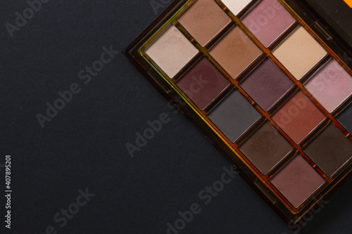 A palette of cosmetics. Cosmetics on a black background. Warm eye shadow.