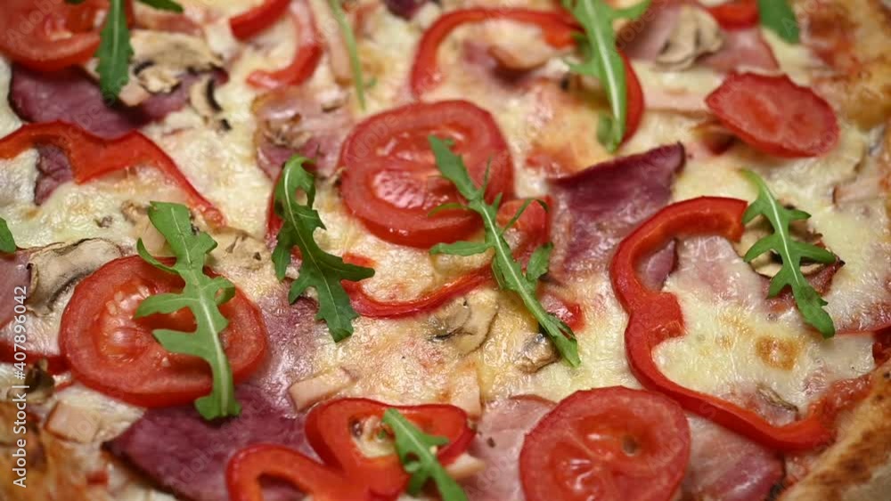 Italian pizza with ham, tomatoes, paprika and arugula on a wooden table. Italian pizza with ham, tomatoes, paprika and arugula on a wooden table.