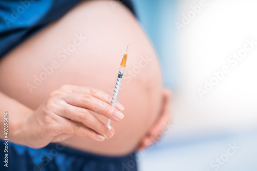 Diabetes in pregnant women. The image of a pregnant woman with an insulin needle.