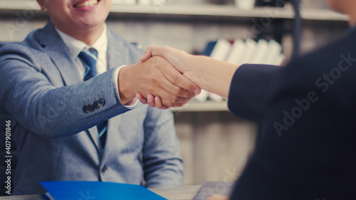 Asian businessman shaking hands partnership deal business while standing indoors in the office, Happy confident accept handshaking employer getting hired at a new job.