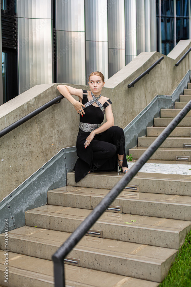 European woman in black clothes sitting on concrete stairs
