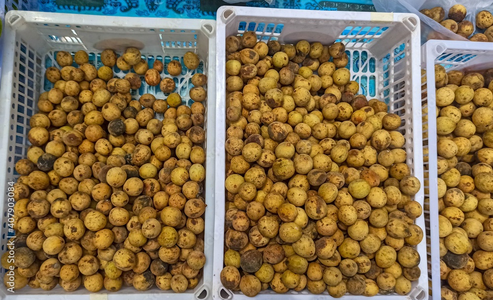 langsat, lansium, or duku pile in a white basket sale in market. Top view of duku.display for selling grocery store . longkong fruits. Thailand fruits