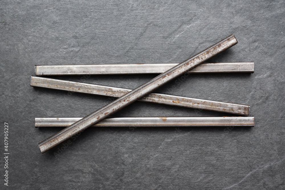 Black metal profile tubes on the black flat lay background. Black metal profile tubes on the black flat lay background.