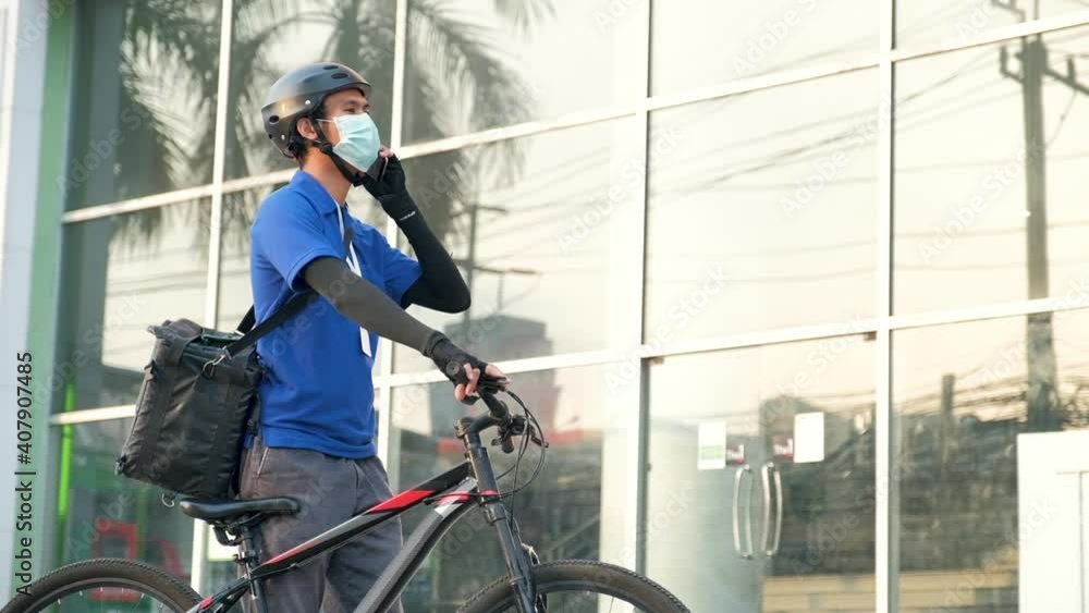 Parcel and food delivery workers are talking to customers before riding their bikes. Guidelines for the delivery of safety masks to wear face masks Parcel and food delivery workers are talking to customers before riding their bikes. Guidelines for the delivery of safety masks to wear face masks