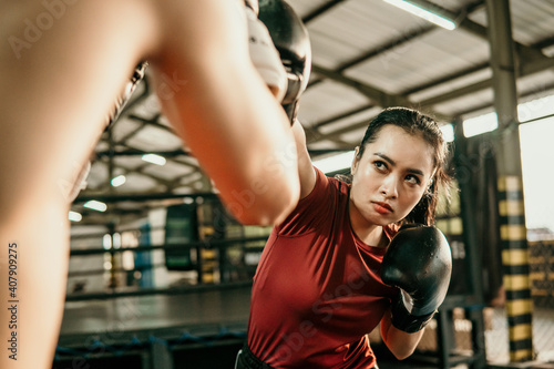 Tablou pe pânză young woman boxer doing exercise hitting punching competing with her opponent at