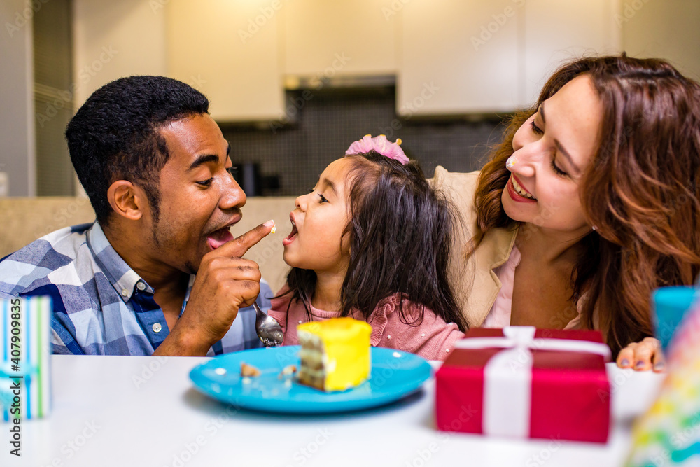 mixed race family habing birthday party in kitchen mixed race family habing birthday party in kitchen