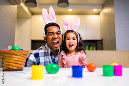 Canvas Print happy mixed race family celebrating Easter, painting eggs with brush smiling and