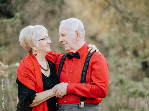 Beautiful elderly couple standing in an embrace in an autumn park