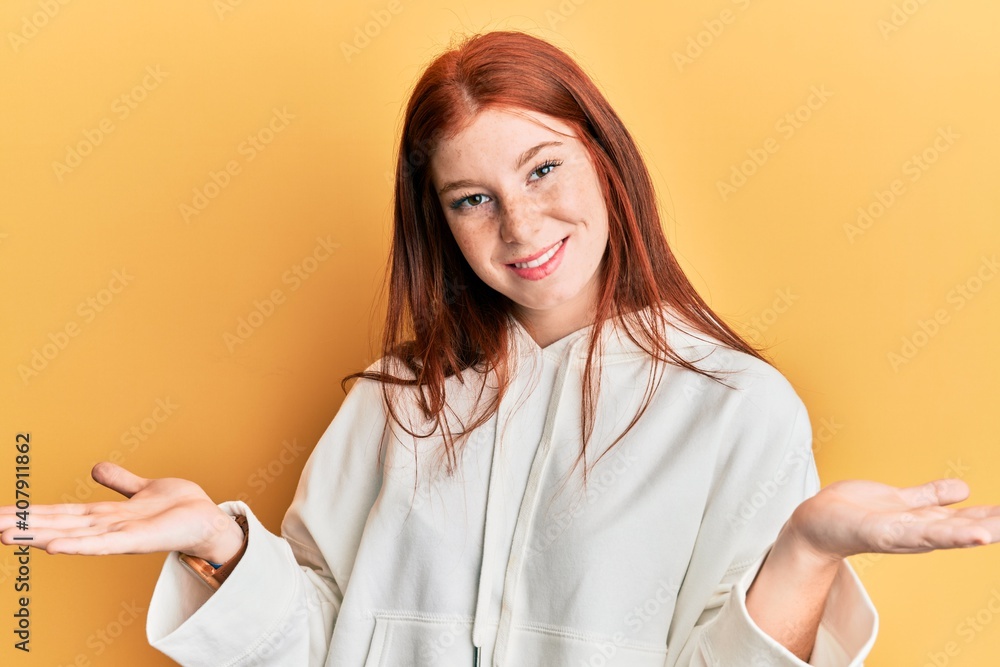 Young red head girl wearing casual sweatshirt clueless and confused expression with arms and hands raised. doubt concept. Young red head girl wearing casual sweatshirt clueless and confused expression with arms and hands raised. doubt concept.