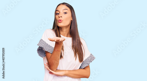 Young hispanic woman wearing casual clothes looking at the camera blowing a kiss with hand on air being lovely and sexy. love expression.