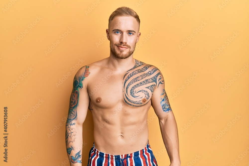 Young caucasian man wearing swimwear shirtless relaxed with serious expression on face. simple and natural looking at the camera.