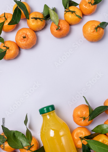 Bottle of Fresh Tangerine Juice with Ripe Tangerines Leaves Healthy Detox Drink Top View Blue Background Horizontal