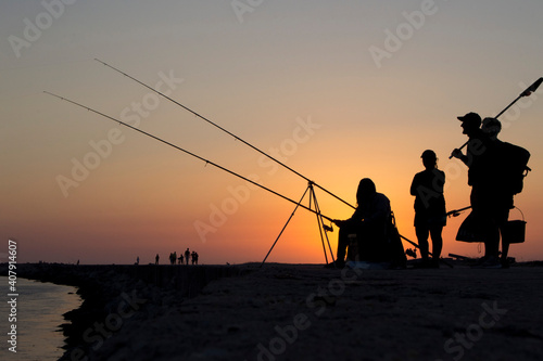 Silhouette of friends are fishing under sunset of a ocean © Marta