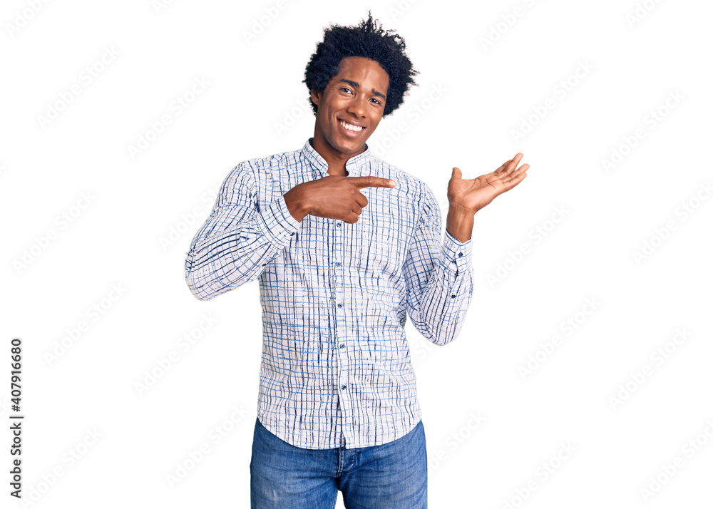 Handsome african american man with afro hair wearing casual clothes amazed and smiling to the camera while presenting with hand and pointing with finger. Handsome african american man with afro hair wearing casual clothes amazed and smiling to the camera while presenting with hand and pointing with finger.