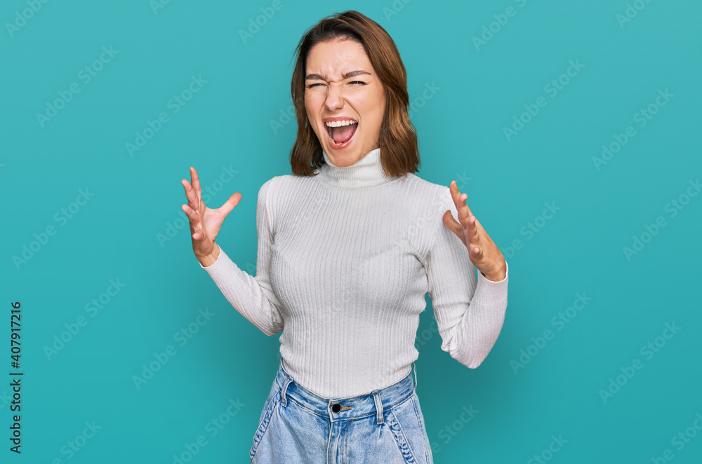 Young caucasian girl wearing casual clothes crazy and mad shouting and yelling with aggressive expression and arms raised. frustration concept. Young caucasian girl wearing casual clothes crazy and mad shouting and yelling with aggressive expression and arms raised. frustration concept.