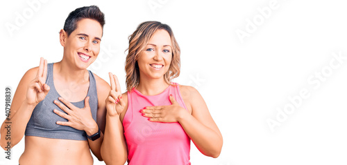 Couple of women wearing sportswear smiling swearing with hand on chest and fingers up, making a loyalty promise oath © Krakenimages.com
