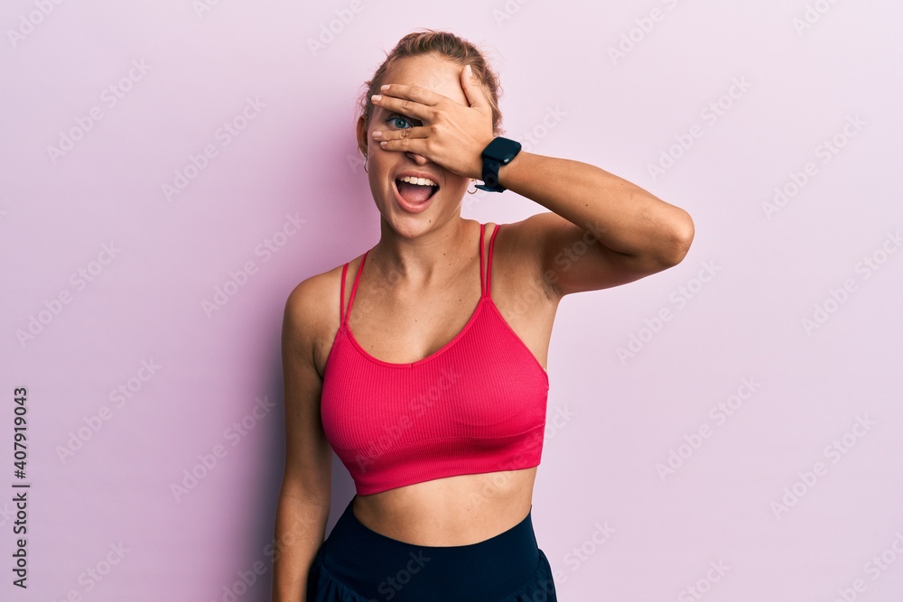Beautiful caucasian woman wearing sportswear peeking in shock covering face and eyes with hand, looking through fingers with embarrassed expression. Beautiful caucasian woman wearing sportswear peeking in shock covering face and eyes with hand, looking through fingers with embarrassed expression.