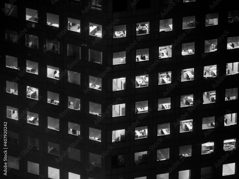monochrome picture of illuminated windows of a tall office building at night monochrome picture of illuminated windows of a tall office building at night