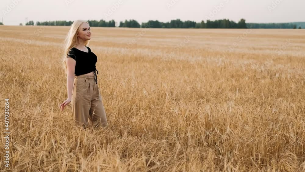 Portrait of pretty girl standing in golden wheat field and smiling. Beautiful young woman on farm looking around with smile on face. Emotions concept Portrait of pretty girl standing in golden wheat field and smiling. Beautiful young woman on farm looking around with smile on face. Emotions concept