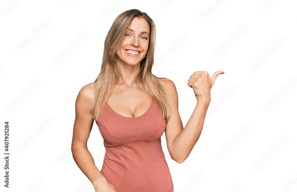Beautiful caucasian woman wearing casual clothes smiling with happy face looking and pointing to the side with thumb up. Beautiful caucasian woman wearing casual clothes smiling with happy face looking and pointing to the side with thumb up.