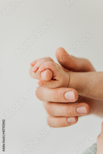 Handle of a newborn close-up in the hands of dad. Newborn baby holds dad's finger in close-up.