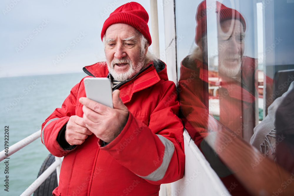 Fisherman looking at smartphone screen and calling to somebody