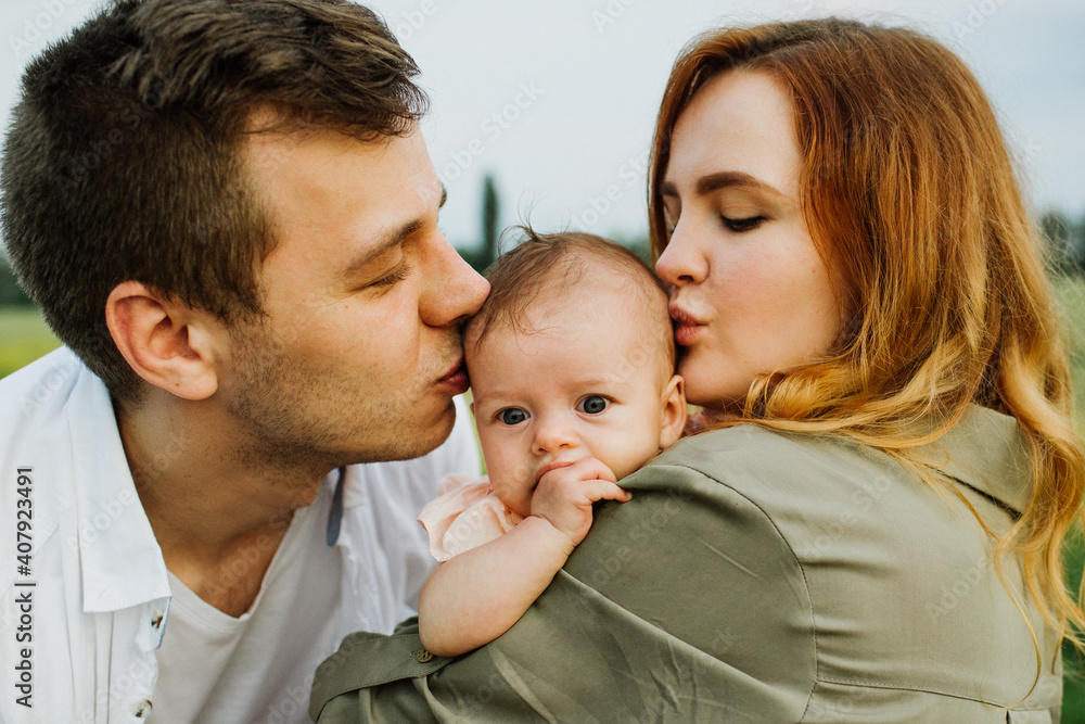 Young parents hug and kiss their newborn daughter in nature. Young parents hug and kiss their newborn daughter in nature.