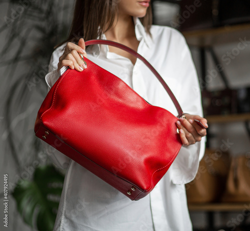 A fashionable woman holds a red leather bag in the office