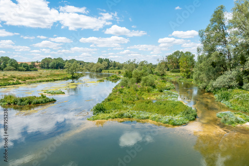 The river Meuse at Troussey, France, view from a bridge, nature scene with small island and sandbanks in the stream and shrub and trees surrounding the water 