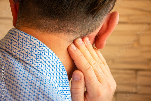 Pain behind ear in area of mastoid process concept photo. Person holds his hand over area behind ear, where pain is suspected due to otitis media, inflammation, noise in ear, hearing loss photo