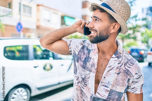 Young hispanic man on vacation smiling happy using smartphone at street of city