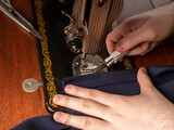 A master sews something from a blue fabric on a sewing machine