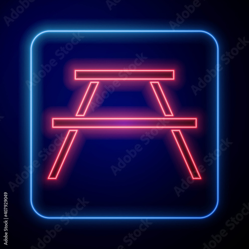 Glowing neon Picnic table with benches on either side of the table icon isolated on blue background. Vector.