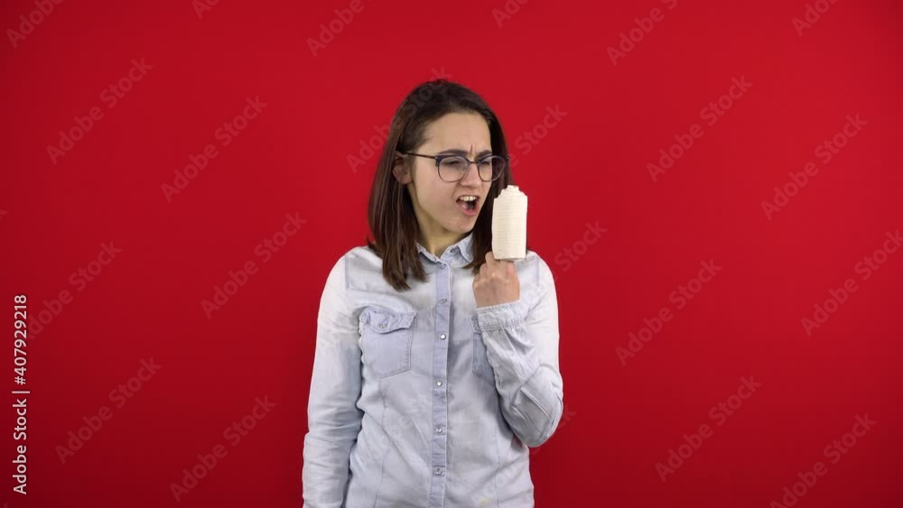 Young woman screaming with rewind bandage finger and shouts. Shooting on a red background. Young woman screaming with rewind bandage finger and shouts. Shooting on a red background.