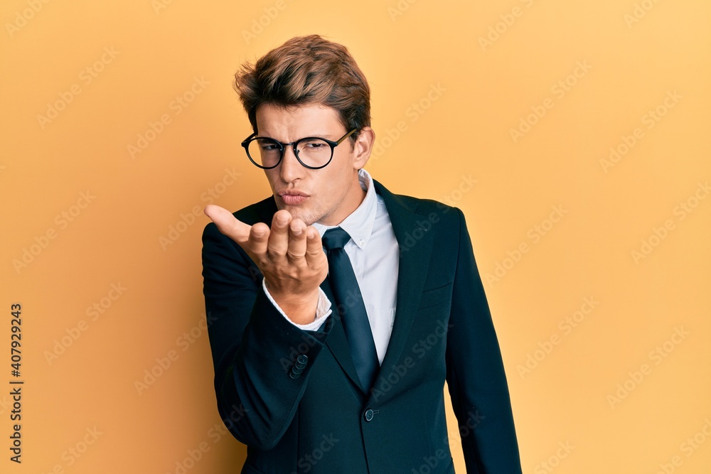 Handsome caucasian man wearing business suit and tie looking at the camera blowing a kiss with hand on air being lovely and sexy. love expression. Handsome caucasian man wearing business suit and tie looking at the camera blowing a kiss with hand on air being lovely and sexy. love expression.
