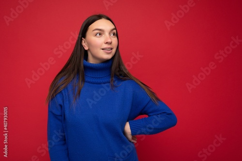 Shot of attractive happy smiling young woman wearing casual outfit standing isolated over colourful background with empty space looking to the side © Ivan Traimak