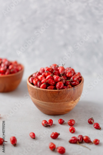 Medicinal plants and herbs. Rose hips berries on concrete background with copy space. Dried fruits for herbal teas and essential oils. Selective focus. Vertical orientation.