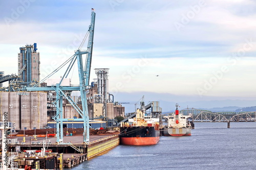 Cargo terminal for loading bulk cargo of cooper concentrates by shore cranes. View of piers and vessels under loading operation. Vancouver, WA, USA. August,2020.