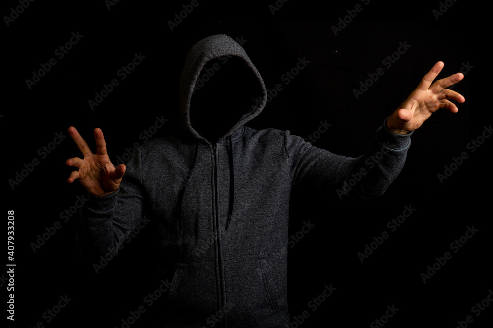 Man in a hood is touching something on a dark background Man in a hood is touching something on a dark background