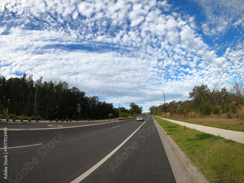 Fantastic shot of a long road and a green forest on cloudy sky background photo