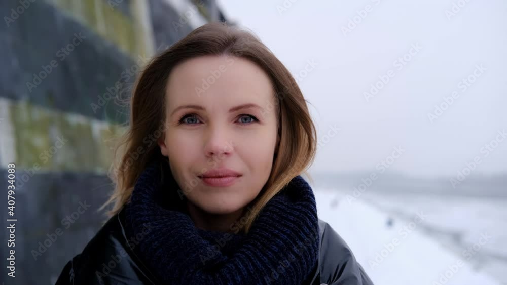 A woman looks at the camera in a scarf on the street. A woman looks at the camera in a scarf on the street.