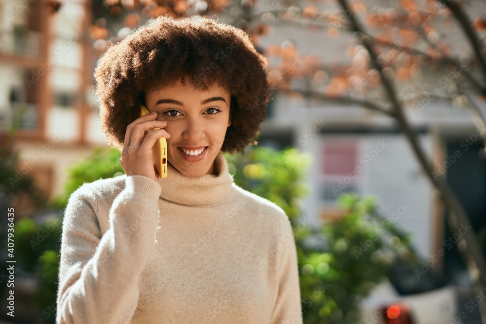 Fototapeta premium Young hispanic girl smiling happy using smartphone at the city.