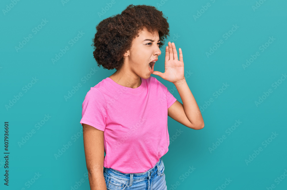Young hispanic girl wearing casual clothes shouting and screaming loud to side with hand on mouth. communication concept. Young hispanic girl wearing casual clothes shouting and screaming loud to side with hand on mouth. communication concept.