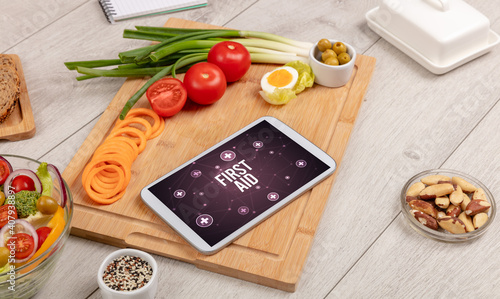 FIRST AID concept in tablet pc with healthy food around, top view