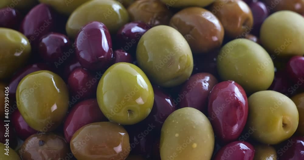 Olives in olive oil spin around themselves on white background. Rotating shot. Mediterranean organic fresh healthy food ingredient, slow motion, close up, macro Olives in olive oil spin around themselves on white background. Rotating shot. Mediterranean organic fresh healthy food ingredient, slow motion, close up, macro