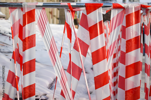 Barrier tape. Renovation work in middle of pedestrian zone. Red and white tape encloses the construction site. Don't come in. Building restoration. An area with red and white plastic barrier tape bloc